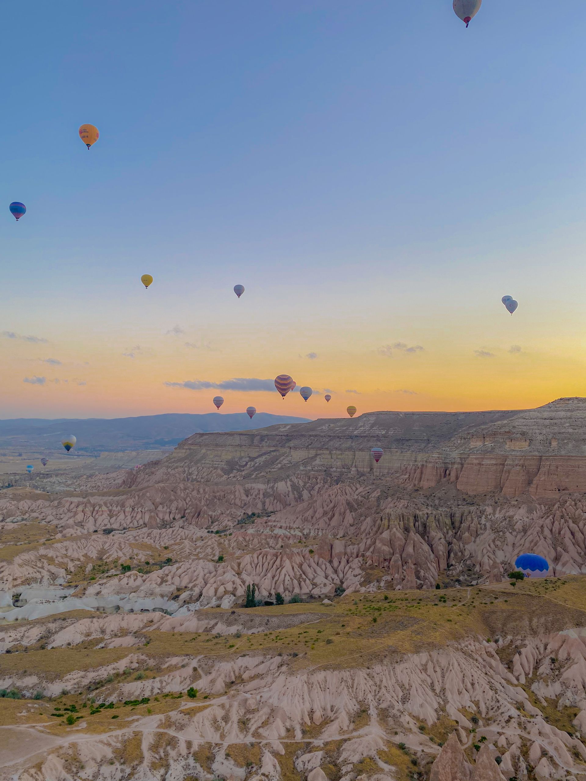 Majestic view of hot air balloons floating over Cappadocia's unique rock formations at sunrise.